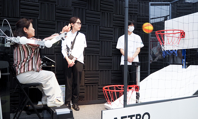 右腕にAetro を装着し、ボールの投げ入れに挑戦する来場者の様子