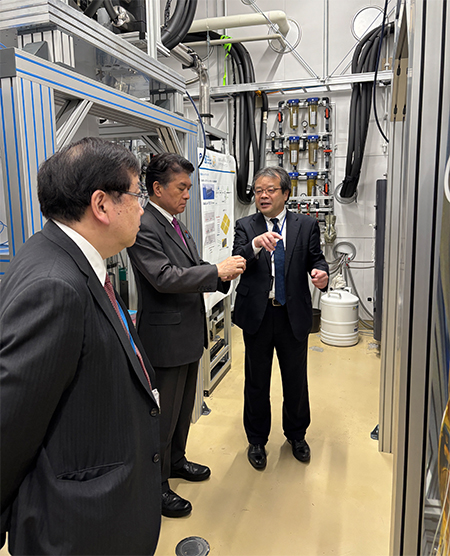 超伝導量子コンピュータ「叡」の前で説明を受けられる小林 副大臣の写真